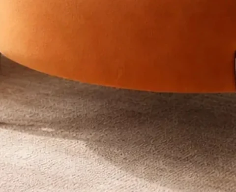Close crop showing the chair's tapered cream-coloured leg with a brass-toned metal tip